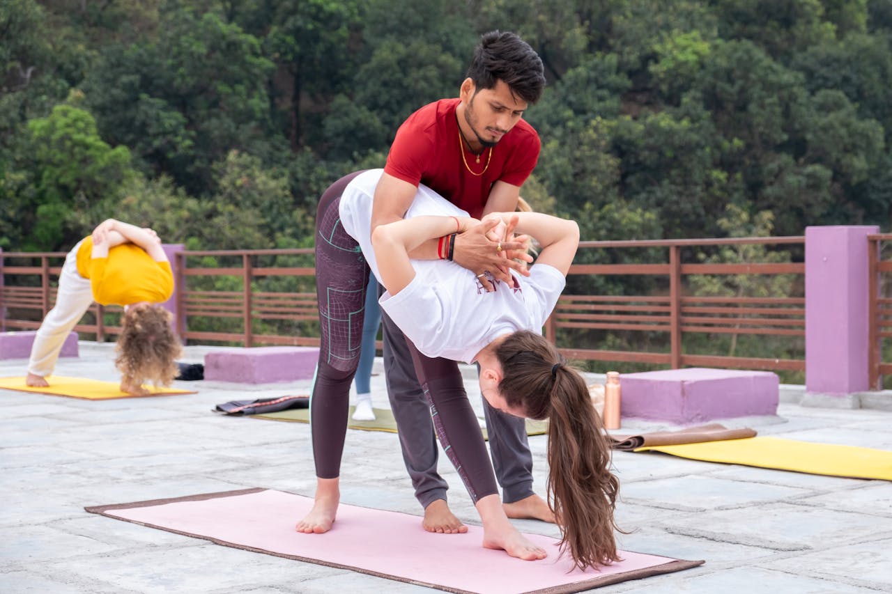 Mastering the First Impression: Your intriguing post title goes here Yoga instructor helps a student with a pose outdoors. Group session amidst nature.
